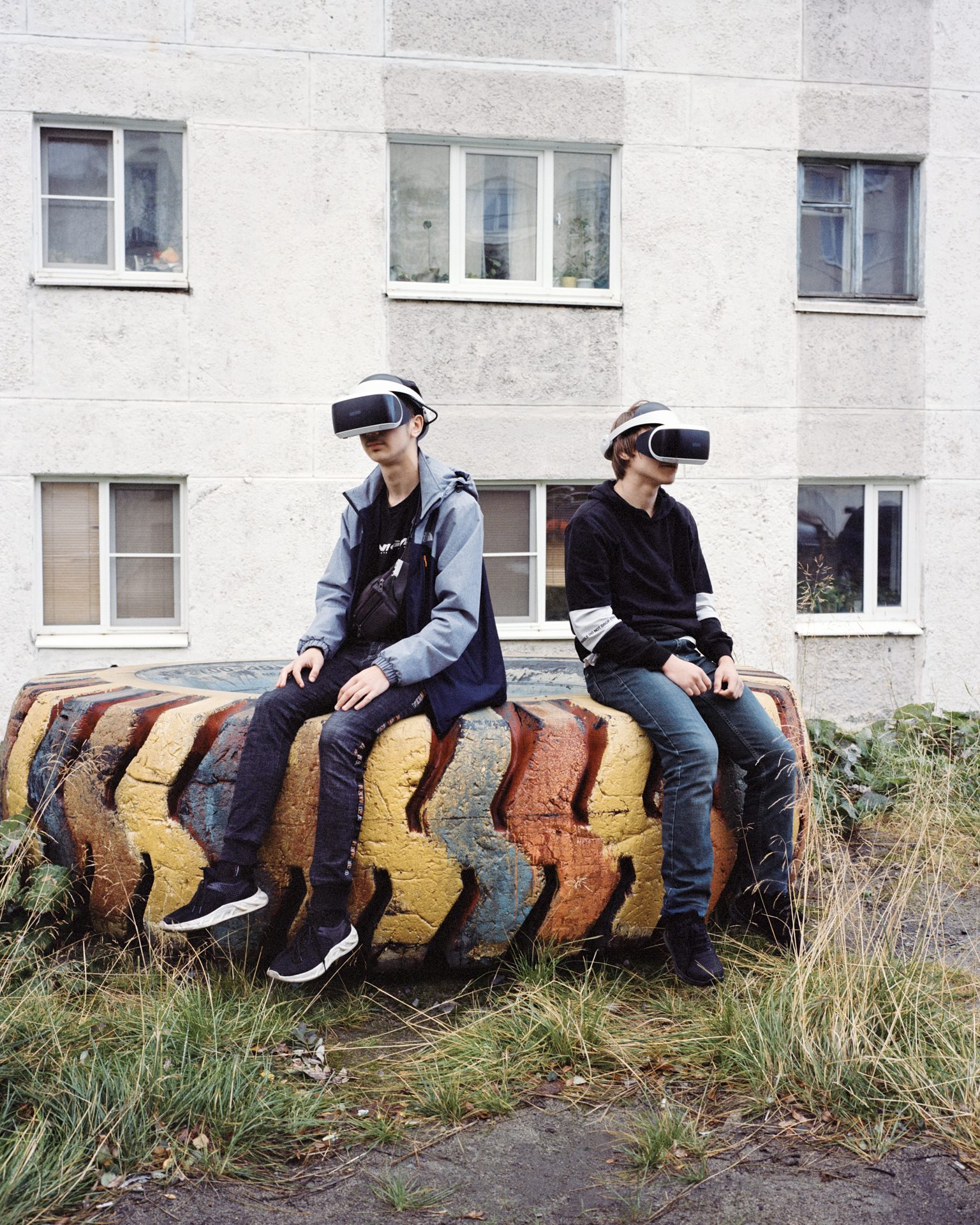 Two teenagers in VR headsets sitting on a painted tyre