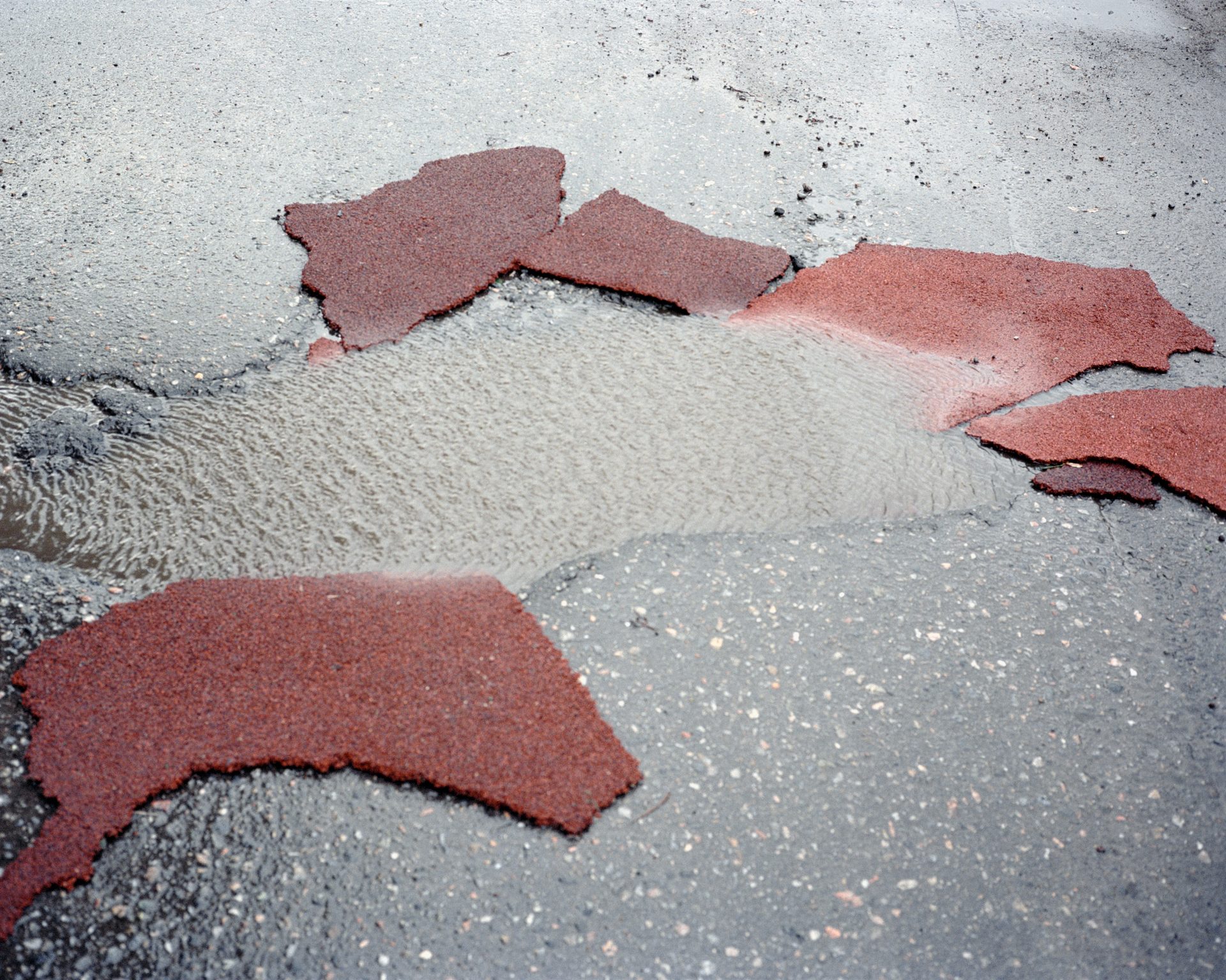 Patches of red asphalt in a flooded road