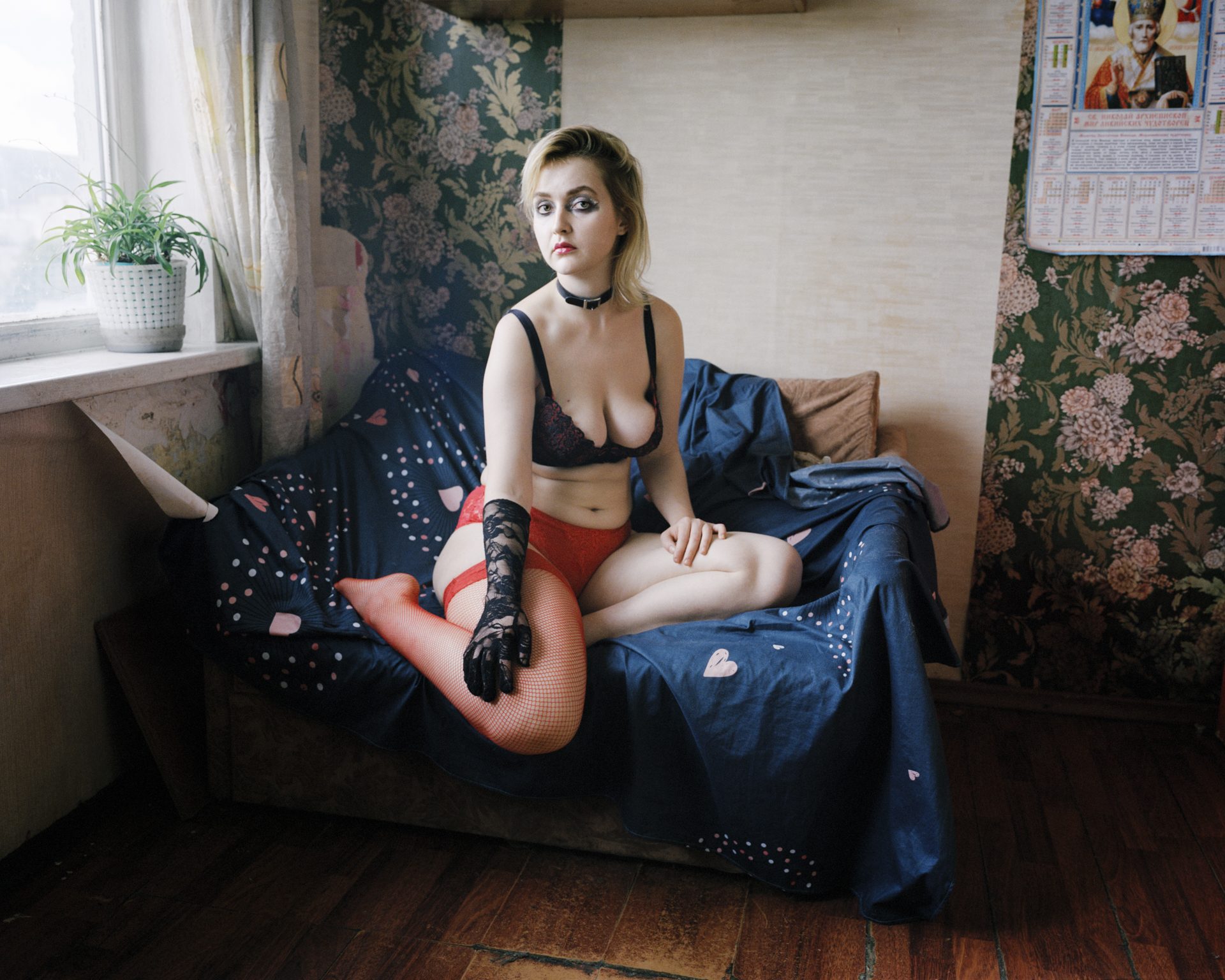 Young woman on a bed below an Orthodox calendar